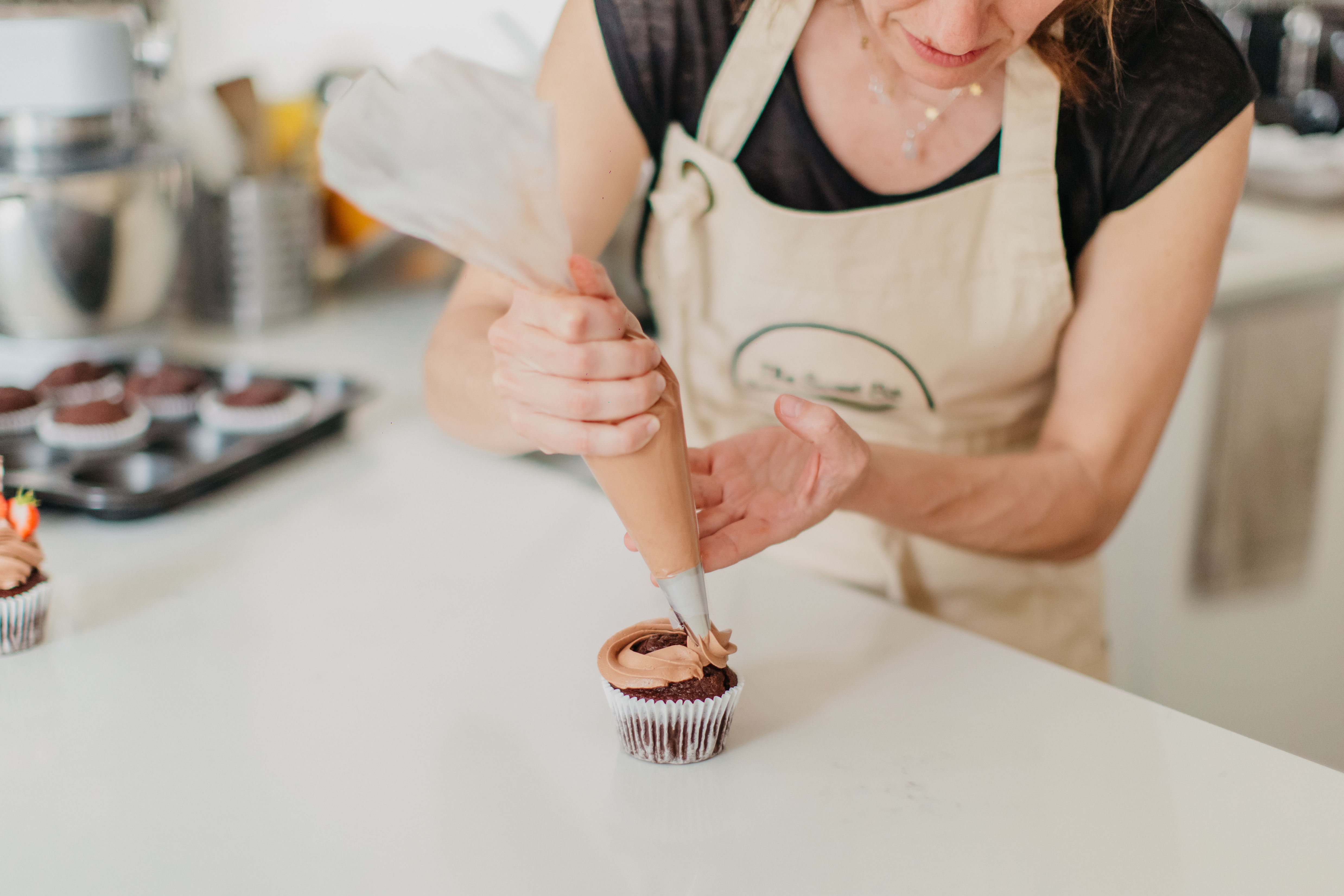 Woman decorating a cupcake with icing in a baking class